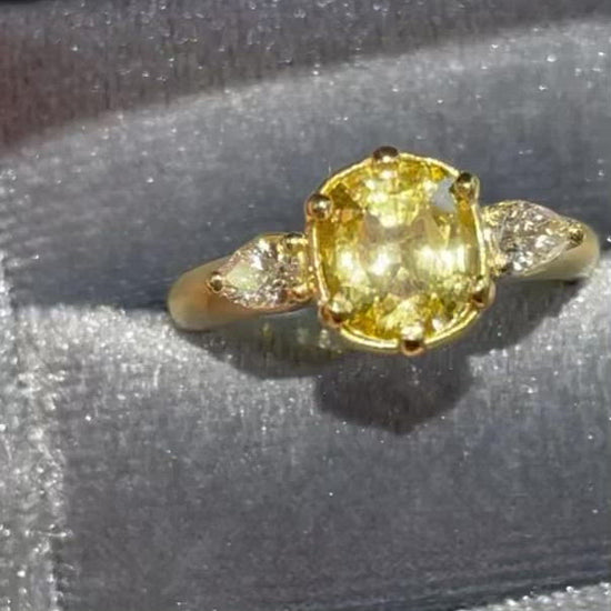 Untreated natural intense yellow sapphire weighing 2.18 ct accented with 2 pear shape white diamonds all set in 18k yellow gold
